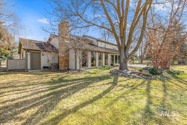 rear view of property with a lawn and a chimney