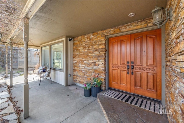 doorway to property with a porch and stone siding