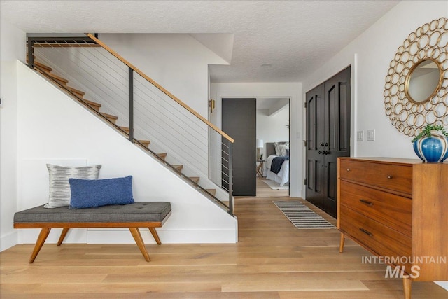 foyer entrance with stairway, wood finished floors, and a textured ceiling