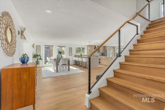 staircase featuring a textured ceiling and wood finished floors