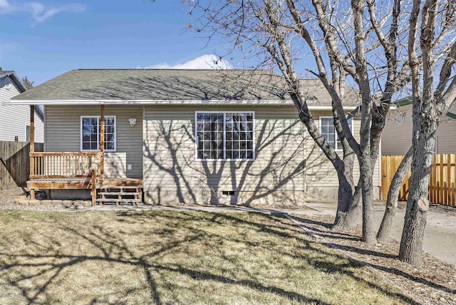 rear view of house with a wooden deck, fence, a shingled roof, and a yard