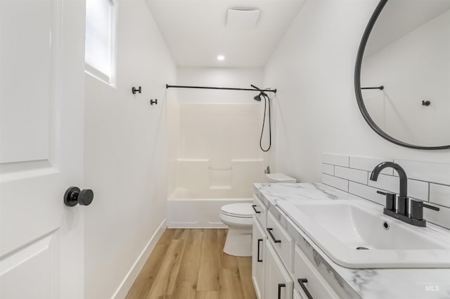 bathroom featuring shower / bath combination, decorative backsplash, toilet, vanity, and wood finished floors