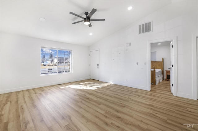 interior space with light wood-style flooring, visible vents, vaulted ceiling, and baseboards