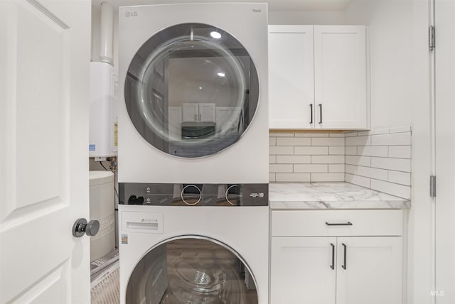 washroom featuring cabinet space and stacked washer / dryer