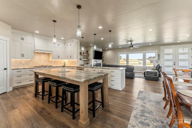 6623 Red Rock Rd, Marsing, ID 83639 - kitchen with a peninsula, a center island, stainless steel gas cooktop, a kitchen bar, and dark wood-type flooring