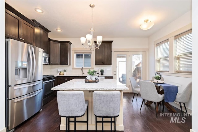 kitchen featuring an inviting chandelier, a sink, dark wood-type flooring, dark brown cabinets, and appliances with stainless steel finishes