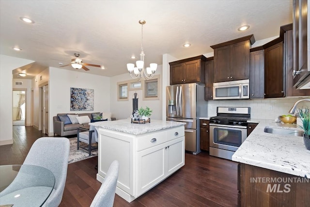 kitchen featuring dark brown cabinets, open floor plan, dark wood-style floors, stainless steel appliances, and a sink