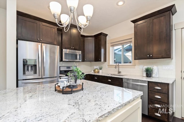 kitchen featuring dark brown cabinets, tasteful backsplash, appliances with stainless steel finishes, and a sink