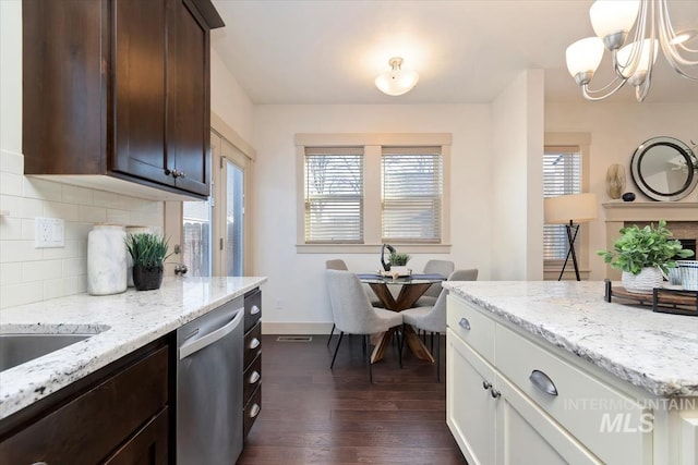 kitchen featuring backsplash, stainless steel dishwasher, dark wood-style floors, dark brown cabinetry, and light stone countertops