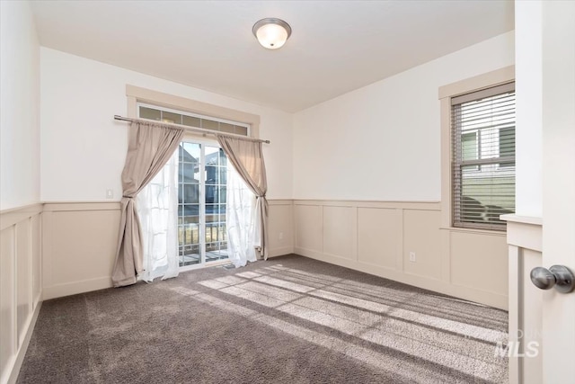 carpeted empty room with a wealth of natural light and wainscoting