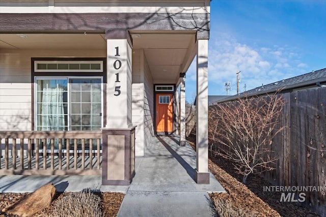 property entrance featuring covered porch and fence