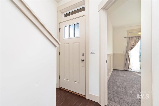 entryway featuring dark wood-type flooring, dark carpet, and wainscoting