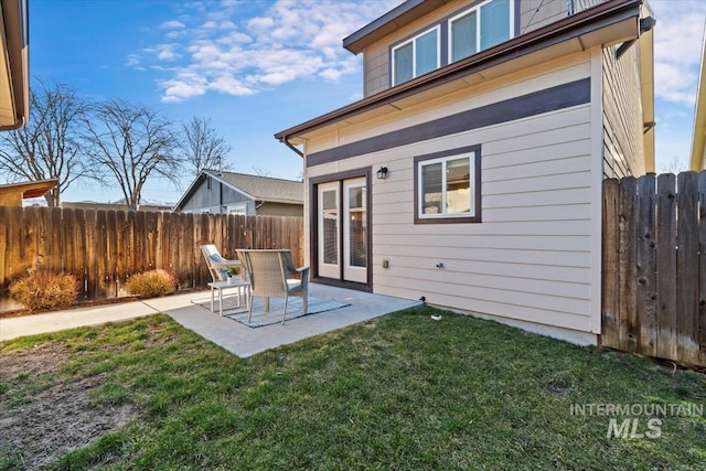 rear view of property with fence, a lawn, and a patio area