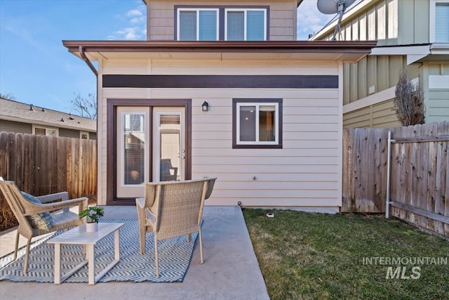 rear view of house featuring fence, board and batten siding, and a patio area