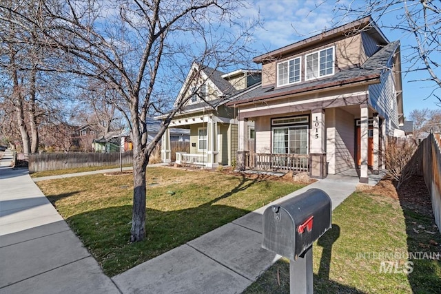 view of front of house with a front yard, fence private yard, and covered porch