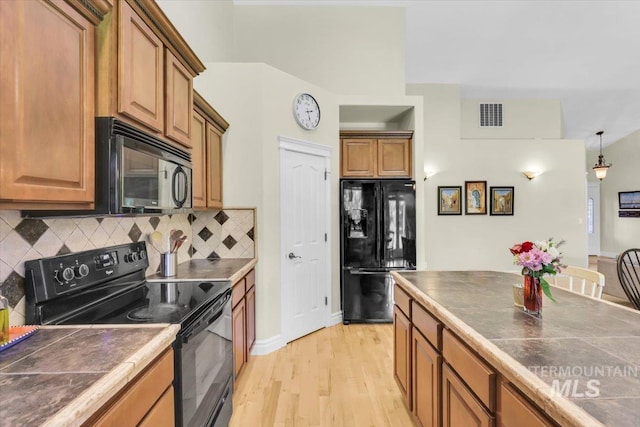2627 E Moog St, Meridian, ID 83646 - kitchen with black appliances, light wood-type flooring, tasteful backsplash, and brown cabinets
