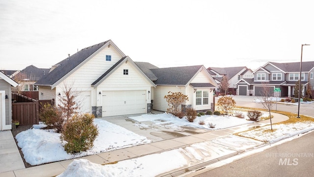 view of front of property featuring driveway, an attached garage, a residential view, and fence