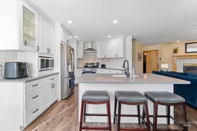 kitchen with tasteful backsplash, wall chimney exhaust hood, appliances with stainless steel finishes, and a breakfast bar area