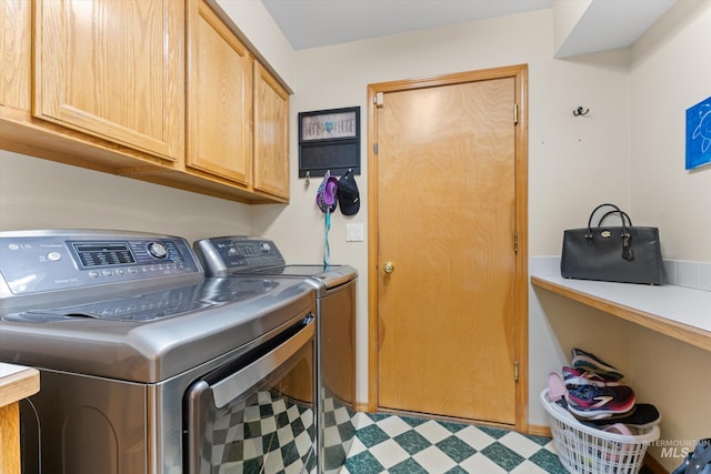 laundry room with washing machine and clothes dryer, tile patterned floors, and cabinet space