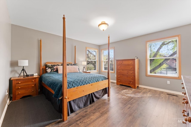 bedroom with baseboards, multiple windows, wood finished floors, and visible vents
