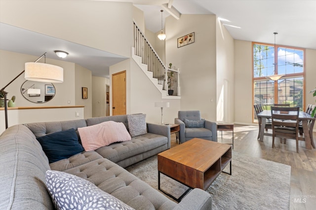 living area with baseboards, wood finished floors, high vaulted ceiling, and stairs