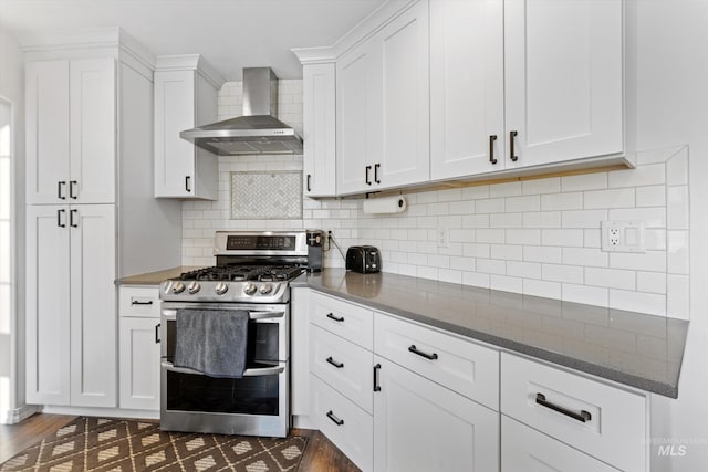 kitchen with dark wood-type flooring, wall chimney range hood, double oven range, and white cabinetry