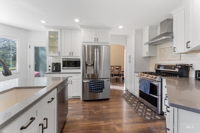 kitchen featuring a sink, light stone countertops, wall chimney exhaust hood, tasteful backsplash, and appliances with stainless steel finishes