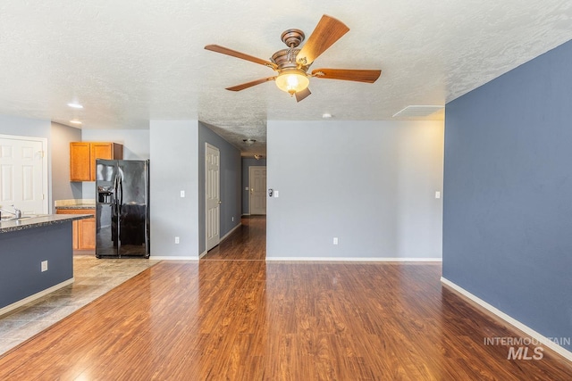 9885 W Tilmont St, Boise, ID 83709 - unfurnished living room featuring light wood-type flooring, a ceiling fan, a textured ceiling, baseboards, and a sink