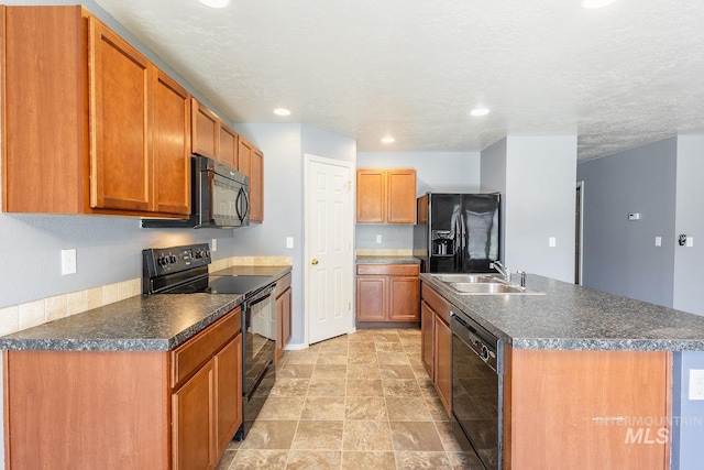 9885 W Tilmont St, Boise, ID 83709 - kitchen with black appliances, a sink, dark countertops, brown cabinets, and an island with sink