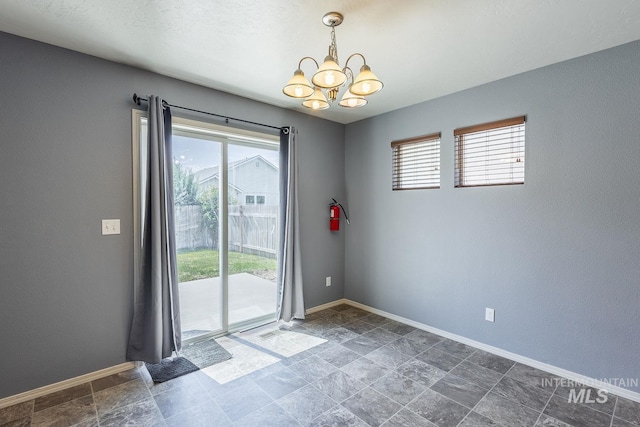 9885 W Tilmont St, Boise, ID 83709 - empty room with a chandelier, baseboards, and dark stone finish floors