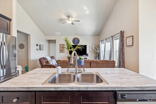 kitchen with a sink, open floor plan, freestanding refrigerator, dark brown cabinetry, and dishwashing machine