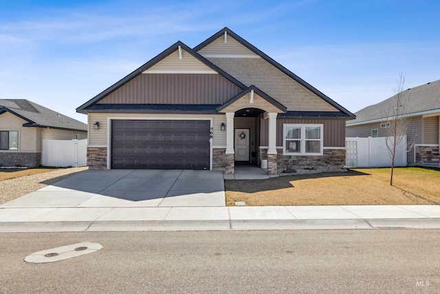 craftsman-style home with concrete driveway, fence, stone siding, and a garage