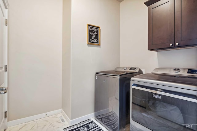 washroom with separate washer and dryer, marble finish floor, baseboards, and cabinet space