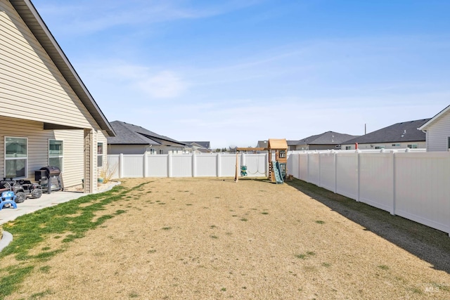 view of yard featuring a patio area, a residential view, a fenced backyard, and a playground