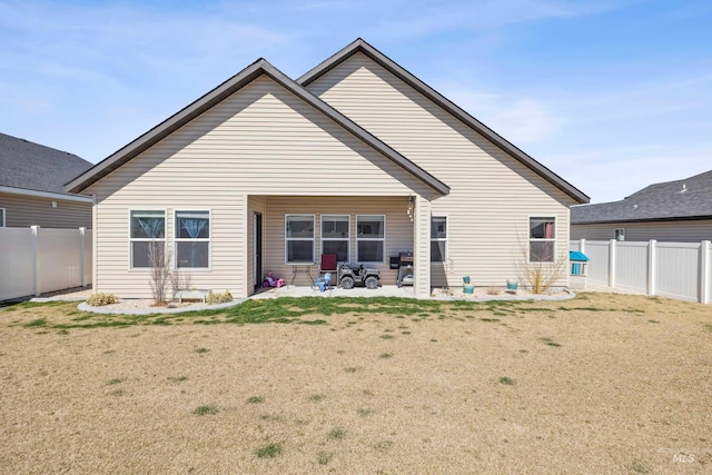 back of property with a patio, a fenced backyard, and a lawn