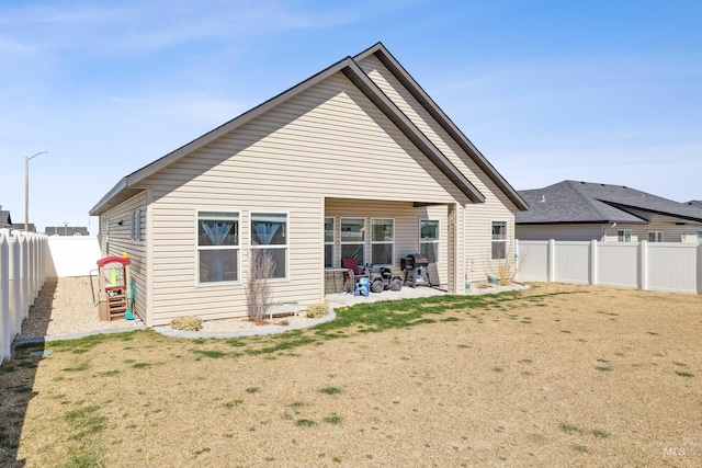 rear view of house with a yard, a patio area, and a fenced backyard