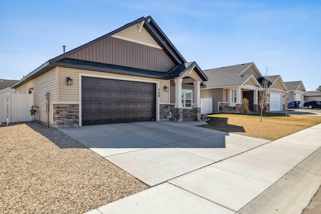 craftsman-style home featuring concrete driveway, stone siding, board and batten siding, an attached garage, and fence