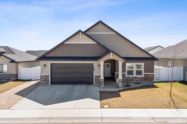 craftsman house with an attached garage, fence, stone siding, and concrete driveway