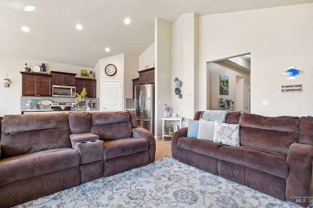 living room featuring high vaulted ceiling, recessed lighting, and light wood-style flooring