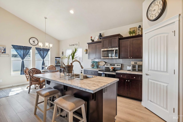 kitchen featuring a sink, light countertops, appliances with stainless steel finishes, a chandelier, and lofted ceiling