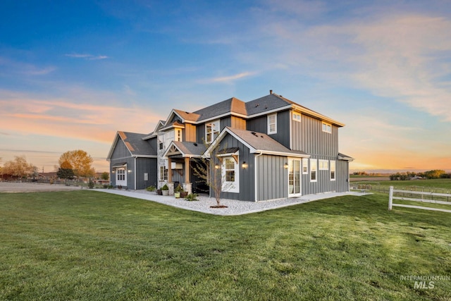 back of property featuring board and batten siding, a yard, and fence