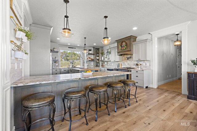 17293 Goodson Rd, Caldwell, ID 83607 - kitchen with light wood-type flooring, a kitchen breakfast bar, decorative backsplash, and light stone countertops
