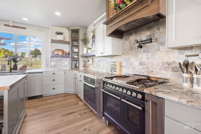 17293 Goodson Rd, Caldwell, ID 83607 - kitchen with range with two ovens, oven, a sink, light wood-style floors, and custom exhaust hood