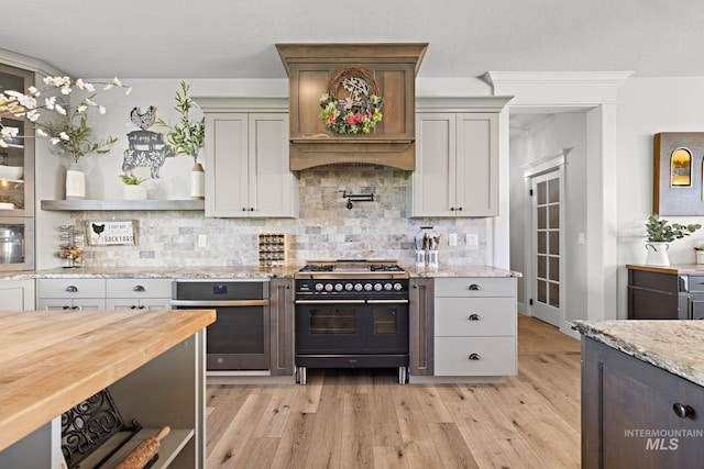 17293 Goodson Rd, Caldwell, ID 83607 - kitchen featuring wood counters, stainless steel oven, double oven range, light wood-type flooring, and decorative backsplash
