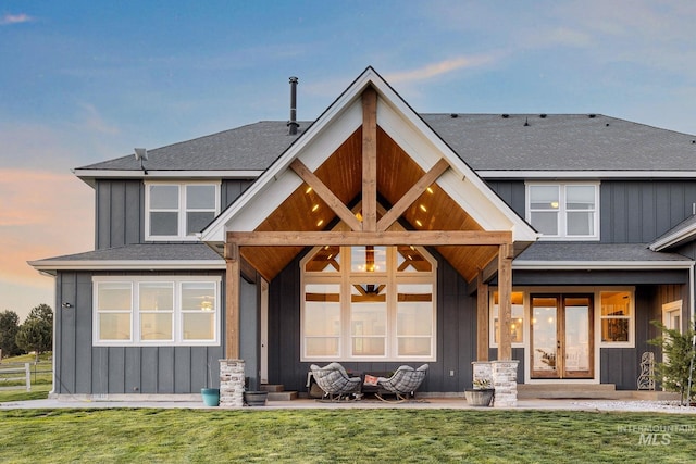 view of front facade featuring board and batten siding, a front yard, french doors, and a shingled roof