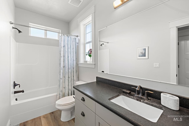 17293 Goodson Rd, Caldwell, ID 83607 - bathroom featuring toilet, wood finished floors, vanity, visible vents, and shower / bath combo with shower curtain