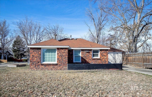 view of front facade with brick siding, fence, and a front lawn