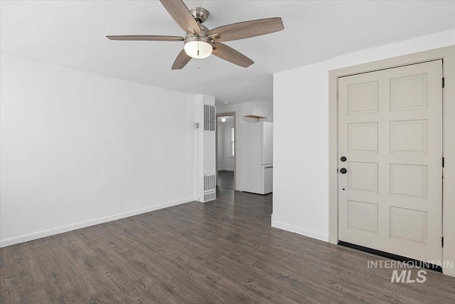 empty room with dark wood-style flooring, a ceiling fan, and baseboards