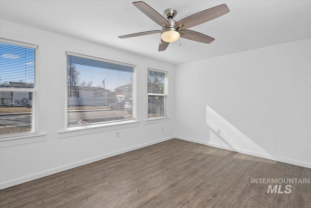 empty room with dark wood-type flooring, a ceiling fan, and baseboards