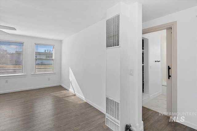 corridor with light wood-style flooring, visible vents, and baseboards